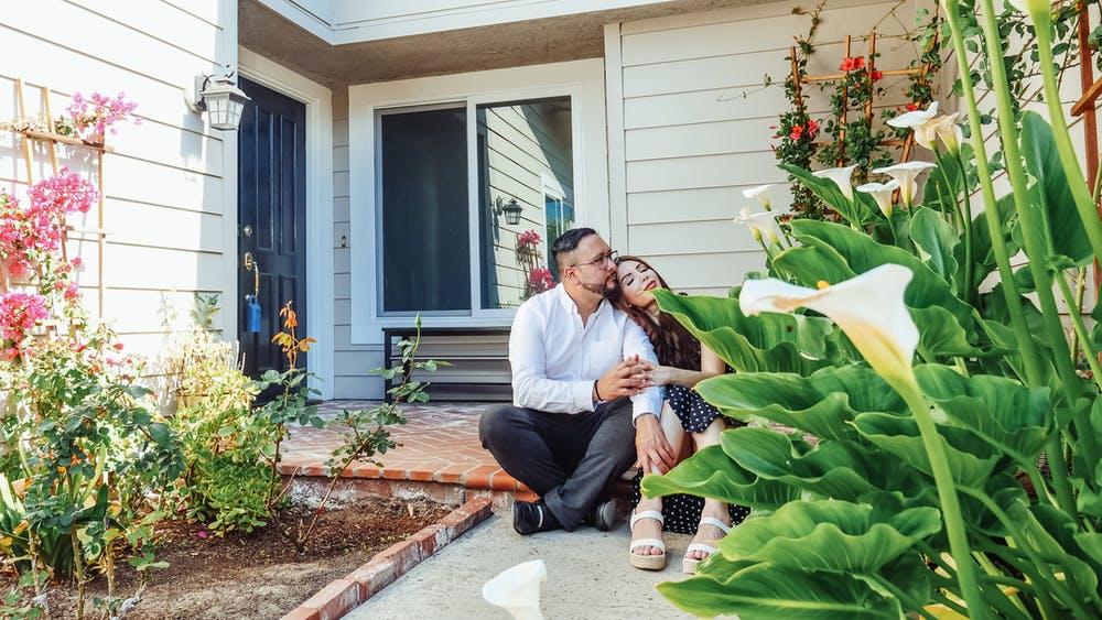 a man and woman sitting on a bench outside a house