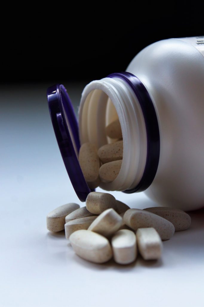 a white container with white and blue pills and a purple tube