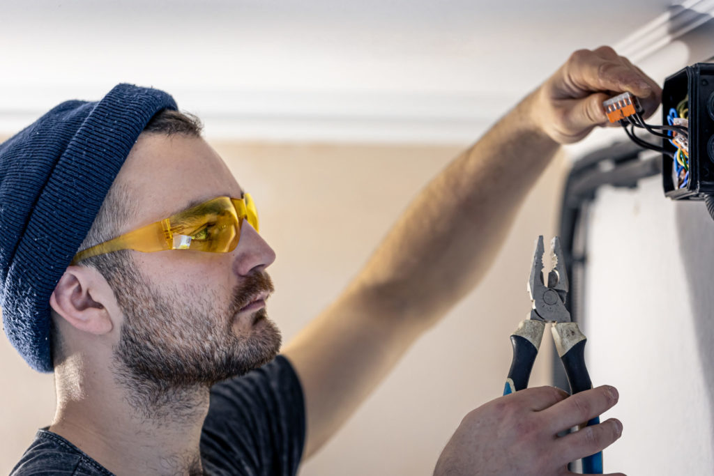 An electrician is mounting electric sockets on the white wall