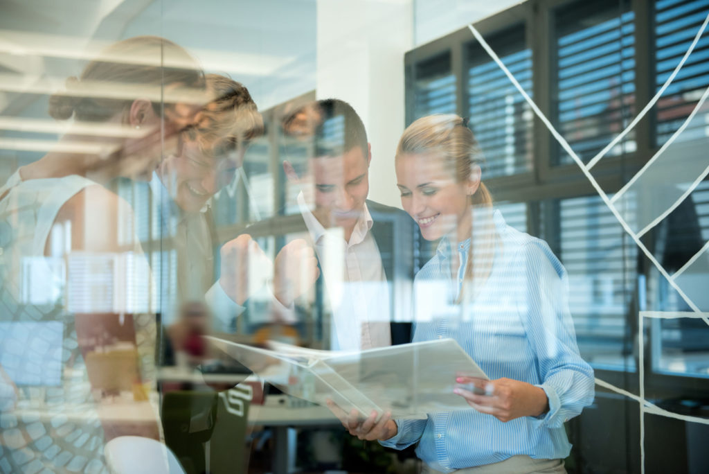 Successful business team behind glass wall in office looking at folder