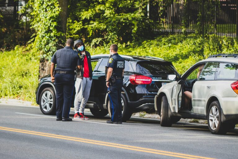 a group of people standing next to a car that has crashed into a tree